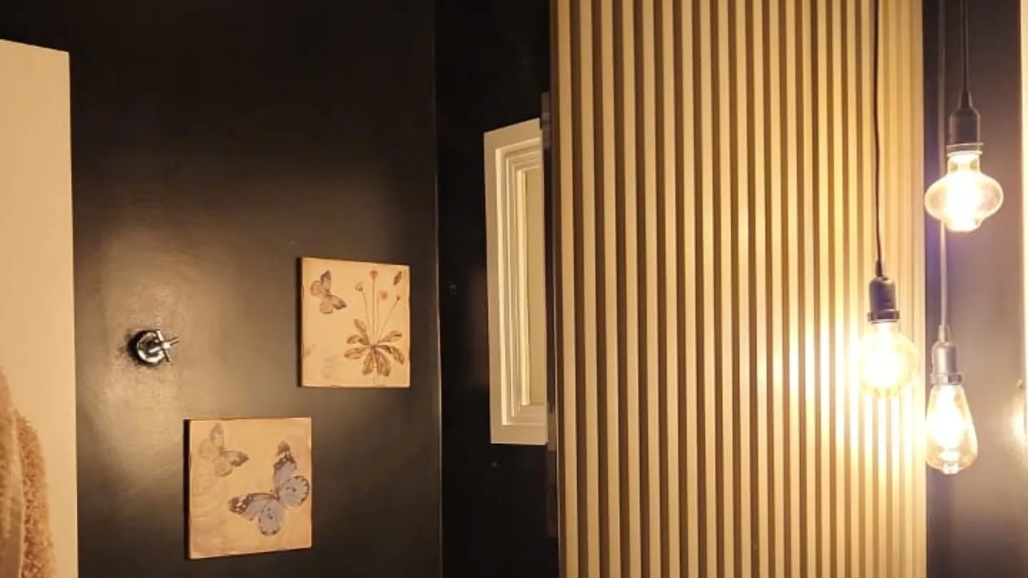 Lavabo com painel ripado de madeira e lâmpadas pendentes